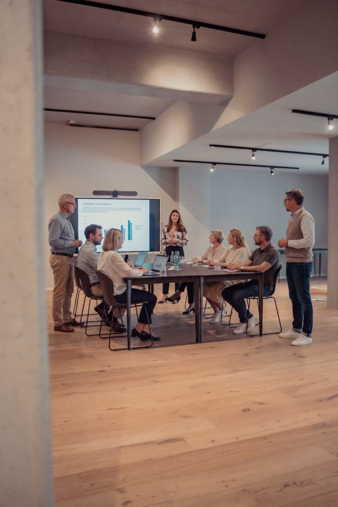 Ein moderner und warmer Meetingroom, in dem gerade eine Konferenz gehalten wird mit mehreren Leuten